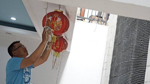 Seorang warga sedang memasang lampion di rumah dalam rangka menyambut tahun baru Imlek. Foto: Helmi Afandi/kumparan