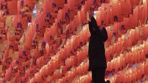 Seorang pengunjung menggantung lentera kertas merah dengan keinginan Tahun Baru selama pertunjukan lentera di Xian, China