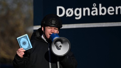 Politisi sayap kanan Rasmus Paludan memegang salinan Al-quran saat protes di depan sebuah masjid di Noerrebro, di Kopenhagen, Denmark, Jumat (27/1/2023). Foto: Sergei Gapon/AFP