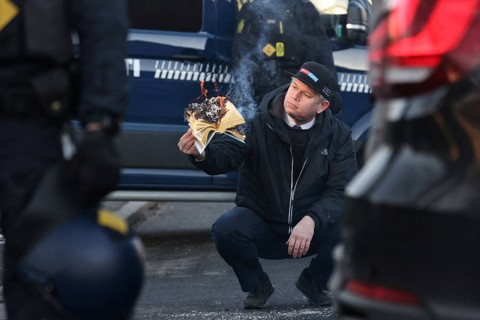 Politisi sayap kanan Rasmus Paludan membakar salinan Al-quran saat protes di depan kedutaan Turki di Kopenhagen, Denmark, Jumat (27/1/2023). Foto: Ritzau Scanpix/Olafur Steinar Gestsson via REUTERS