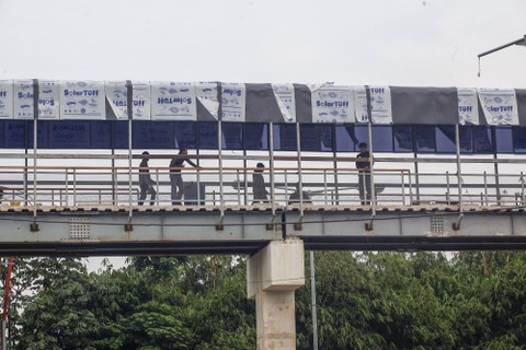Pekerja menyelesaikan proyek pembangunan jembatan multiguna (skybridge) di Bojonggede, Kabupaten Bogor, Jawa Barat, Senin (30/1/2023). Foto: Yulius Satria Wijaya/Antara Foto