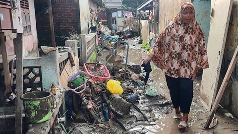 Seorang warga berjalan di antara sampah sisa banjir Manado.