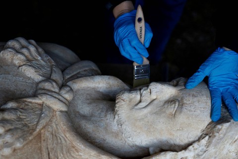 Pemulih dari taman arkeologi Appia Antica Sara Iovine membersihkan patung kaisar Romawi setelah ditemukan di saluran pembuangan di dekat Appian Way lama, Roma, Italia. Foto: Guglielmo Mangiapane/REUTERS