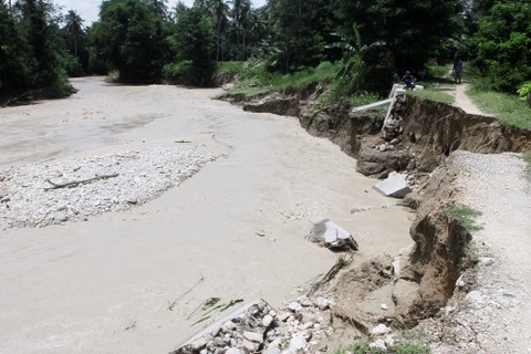 Sejumlah warga duduk di pinggiran sungai menyaksikan derasnya aliran air akibat jebolnya pintu air Bendungan Oesao di Desa Pukdale, Kabupaten Kupang, NTT, Minggu (5/2/2023). Foto: Kornelis Kaha/Antara Foto
