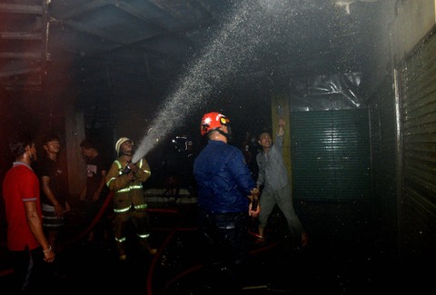 Sejumlah petugas pemadam kebakaran berusaha memadamkan api saat terjadi kebakaran di Pasar Terong, Makassar, Sulawesi Selatan, Minggu (5/2/2023) malam. Foto: Abriawan Abhe/Antara Foto