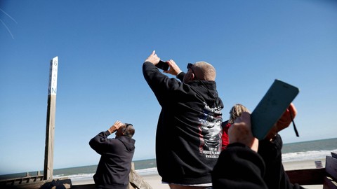 Warga melihat balon mata-mata yang diduga milik China melayang ke laut setelah ditembak jatuh di lepas pantai di Surfside Beach, Carolina Selatan, AS. Foto: Randall Hill/REUTERS