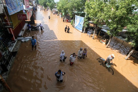 Warga melintasi banjir di Desa Kedawung, Grati, Pasuruan, Jawa Timur, Sabtu (11/2/2023). Foto: Umarul Faruq/ANTARA FOTO