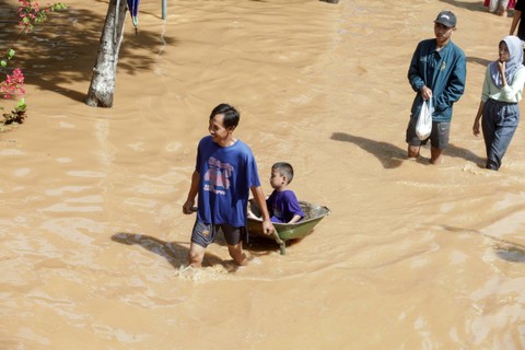 Warga melintasi banjir di Desa Kedawung, Grati, Pasuruan, Jawa Timur, Sabtu (11/2/2023). Foto: Umarul Faruq/ANTARA FOTO
