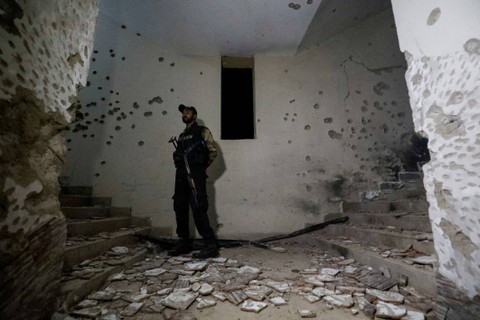 Seorang petugas polisi mengamankan sebuah lokasi saat ia berdiri di tengah kerusakan akibat serangan terhadap sebuah kantor polisi di Karachi, Pakistan, Jumat (17/2/2023). Foto: Akhtar Soomro/REUTERS