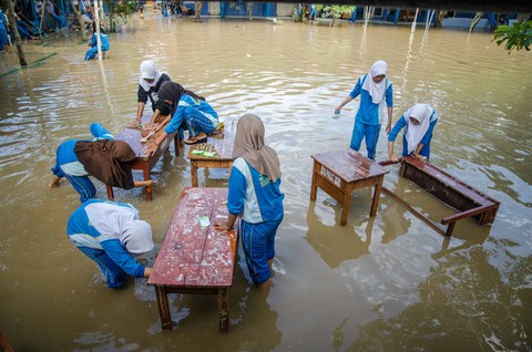 Siswa membersihkan meja kelas pada genangan banjir di SMPN 1 Telukjambe Barat, Karangligar, Kabupaten Karawang, Jawa Barat, Jumat (3/3/2023). Foto: Novrian Arbi/ANTARA FOTO