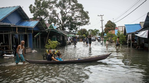 Warga menggunakan perahu melintasi jalan yang terendam banjir di Desa Sungai Rangas Ulu, Kabupaten Banjar, Kalimantan Selatan, Sabtu (4/3/2023). Foto: Bayu Pratama S/Antara Foto