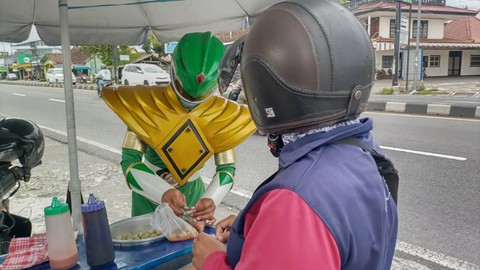 Seorang penjual cilok bernama Juwanso (40) di Kabupaten Sleman mengenakan kostum Power Rangers hijau saat berdagang, Sabtu (4/3). Foto: Arfiansyah Panji Purnandaru/kumparan