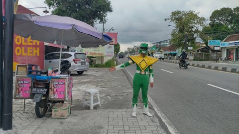 Seorang penjual cilok bernama Juwanso (40) di Kabupaten Sleman mengenakan kostum Power Rangers hijau saat berdagang, Sabtu (4/3). Foto: Arfiansyah Panji Purnandaru/kumparan