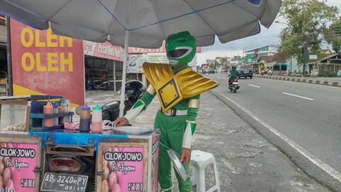 Seorang penjual cilok bernama Juwanso (40) di Kabupaten Sleman mengenakan kostum Power Rangers hijau saat berdagang, Sabtu (4/3). Foto: Arfiansyah Panji Purnandaru/kumparan