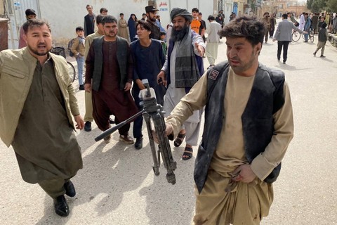 Seorang jurnalis yang terluka (kanan) memegang tripod kamera di dekat lokasi ledakan bom selama acara memperingati media di Mazar-i-Sharif, Afghanistan pada Sabtu (11/3/2023). Foto: Atif Aryan/AFP