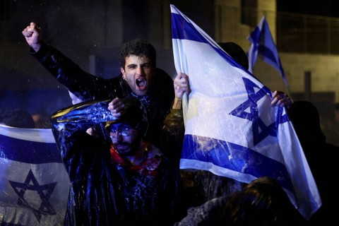 Orang-orang melakukan demonstrasi setelah Perdana Menteri Israel Benjamin Netanyahu memecat menteri pertahanan dan pemerintah koalisi nasionalisnya melanjutkan pemeriksaan yudisialnya, di Yerusalem, Minggu (26/3/2023). Foto: Ronen Zvulun/REUTERS