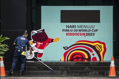 Petugas membersihkan lantai di dekat papan promosi Piala Dunia U-20 Indonesia 2023 di kawasan GBK Arena, Jakarta, Kamis (30/3/2023). Foto: Aprillio Akbar/Antara Foto