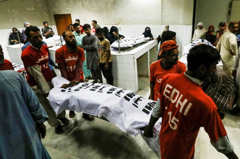 Petugas penyelamat memindahkan jenazah seorang korban, yang tewas akibat terinjak-injak di pusat distribusi bansos di Karachi, Pakistan 31 Maret 2023.. Foto: Akhtar Soomro/Reuters
