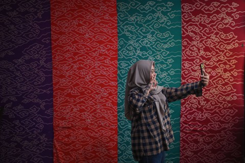 Pengunjung berswa foto dengan latar belakang kain-kain batik koleksi Trupark Museum di kawasan Sentra Batik Trusmi, Cirebon, Jawa Barat, Senin (17/4/2023).  Foto: Aditya Pradana Putra/ANTARA FOTO