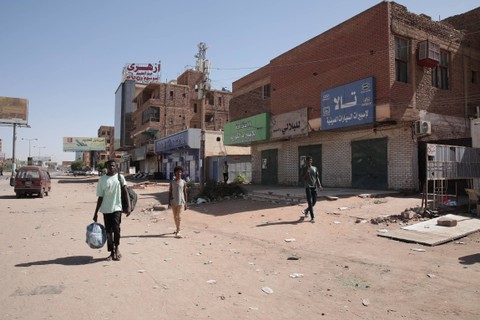 Orang-orang berjalan melewati toko-toko yang tutup di Khartoum, Sudan, Selasa (18/4/2023). Foto: Marwan Ali/AP Photo