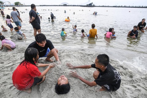 Pengunjung bermain pasir di kawasan pantai Ancol, Jakarta, Minggu (23/4/2023). Foto: M Risyal Hidayat/Antara Foto 