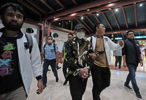 Petugas Dittipidsiber Bareskrim Polri membawa peneliti dari Badan Riset dan Inovasi Nasional (BRIN) Andi Pangerang Hasanuddin (tengah) setibanya di Terminal 2 Bandara Soekarno, Hatta, Tangerang, Banten, Minggu (30/4/2023). Foto: Muhammad Iqbal/Antara Foto