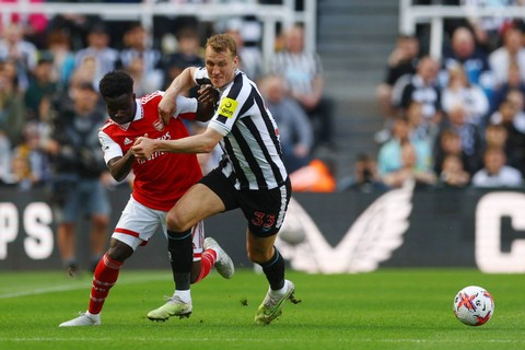 Pemain Newcastle United Dan Burn berebut bola dengan pemain Arsenal Bukayo Saka pada pertandingan lanjutan Liga Inggris di Stadion St. James Park, Newcastle, Inggris, Minggu (7/5/2023).  Foto: Lee Smith/REUTERS