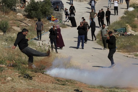 Seorang pengunjuk rasa Palestina menendang tabung gas air mata selama ketika buldoser tentara Israel menghancurkan sebuah sekolah, di desa Jabbet al-Dhib, sebelah timur Bethlehem di Tepi Barat yang diduduki Israel, Minggu (7/5/2023). Foto: Hazem Bader/AFP