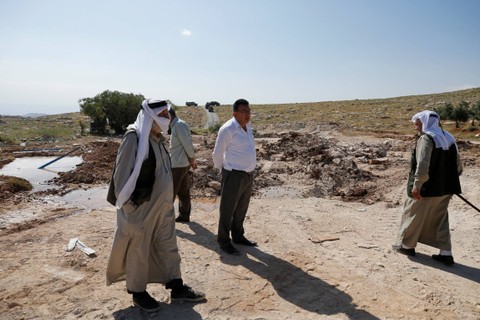 Warga Palestina berdiri di atas puing-puing setelah otoritas Israel menghancurkan sekolah di desa Jabbet al-Dhib, dekat Bethlehem di Tepi Barat yang diduduki Israel, Minggu (7/5/2023). Foto: Mussa Qawasma/REUTERS