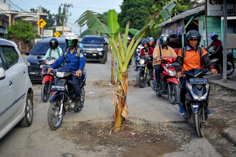 Pengendara melintasi Jalan DR. Siwabessy yang rusak dan ditanami pohon pisang di Telanaipura, Jambi, Selasa (4/4/2023). Foto: Wahdi Septiawan/Antara Foto
