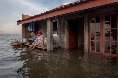 Warga menanti surutnya rob di depan rumahnya di Desa Sidogemah, Kecamatan Sayung, Kabupaten Demak, Jawa Tengah, Minggu (14/5/2023). Foto: Aji Styawan/ANTARA FOTO