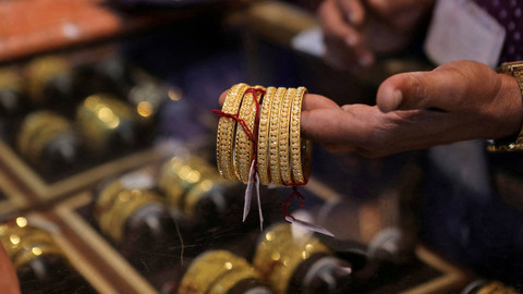 Pedagang menunjukkan model perhiasan emas. Foto: Niharika Kulkarni/Reuters