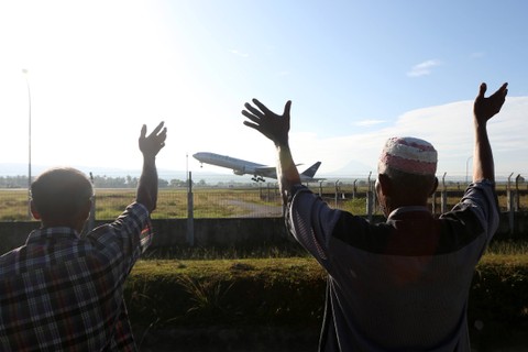 Warga melambaikan tangan pada pesawat Garuda boing 777-300 ER yang membawa 393 jemaah calon haji kloter pertama embarkasi Aceh di Bandara Internasional Sultan Iskandar Muda, Aceh Besar, Aceh, Rabu (24/5/2023).  Foto: Irwansyah Putra/ANTARA FOTO