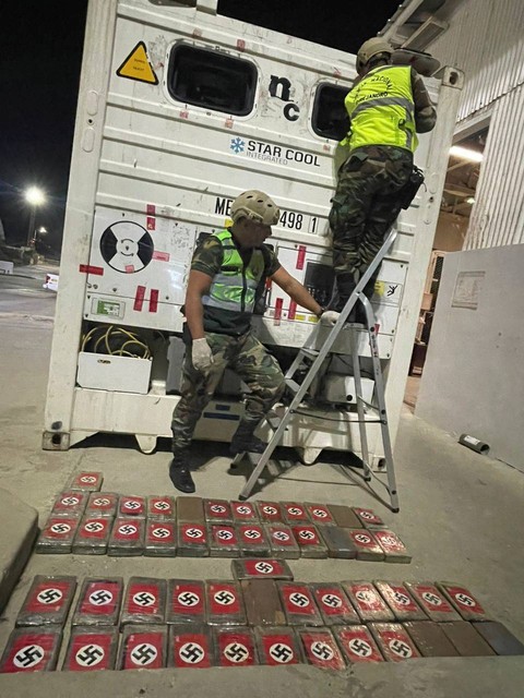 Petugas polisi berdiri di samping kontainer berpendingin dan menyita paket kokain yang ditandai dengan swastika Nazi di pelabuhan Paita, Peru, Jumat (26/5/2023). Foto: Peru Police/Handout via REUTERS