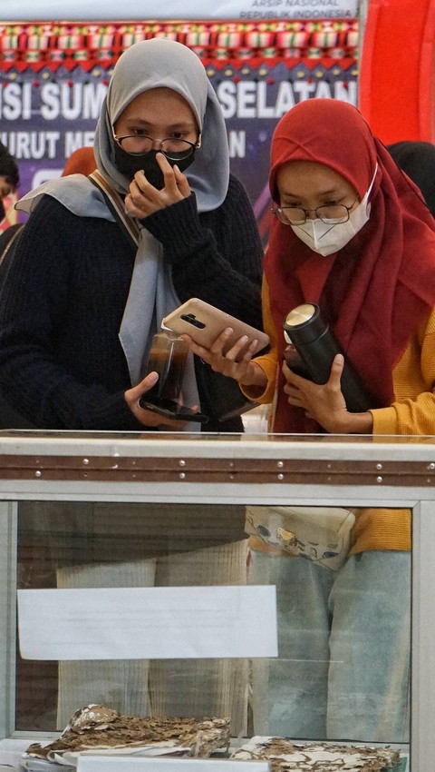 Dua orang pengunjung yang melihat arsip lawas di stan Dinas Kearsipan Prov Sumsel pada event Sriwijaya Expo 2023, Minggu (28/5) Foto: abp/Urban Id