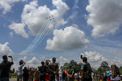 Pengunjung menyaksikan aksi Jupiter Aerobatic Team (JAT) TNI AU saat bermanuver di atas Lanud Roesmin Nurjadin, di Pekanbaru, Riau, Minggu (28/5/2023). Foto: Rony Muharrman/Antara Foto