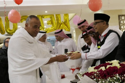 Ketua PPIH Arab Saudi Subhan Cholid (kanan) menyerahkan kue kepada jemaah calon haji kloter SOC 01 setibanya di Hotel kawasan Makkah, Arab Saudi, Kamis (1/6/2023). Foto: Wahyu Putro A/ANTARA FOTO