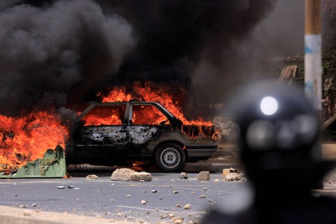 Orang-orang memadamkan barikade yang dibakar oleh pendukung pemimpin oposisi Senegal Ousmane Sonko, setelah Sonko dijatuhi hukuman penjara di Dakar, Senegal, Kamis (1/6/2023). Foto: Zohra Bensemra/REUTERS