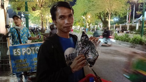 Pedagang asongan yang mendapatkan kaus dan amplop dai Presiden Jokowi. Foto: Arfiansyah Panji Purnandaru/kumparan