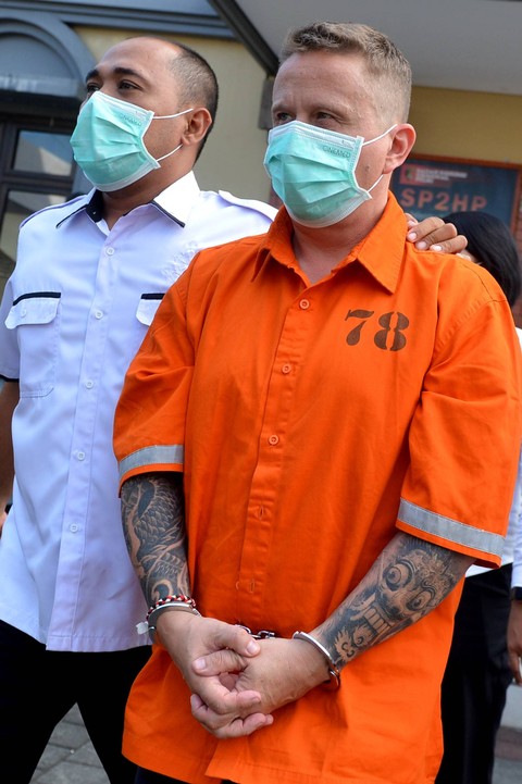 Polisi menggiring warga negara Kanada berinisial SG (kanan) di Gedung Ruang Pelayanan Khusus (RPK) Polda Bali, Denpasar, Bali, Senin (22/5/2023). Foto: Fikri Yusuf/ANTARA FOTO