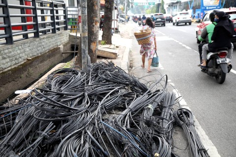 Pengendara melintas di dekat tumpukan kabel jaringan utilitas di kawasan Mampang, Jakarta Selatan, Senin (5/6/2023). Foto: Fitra Andrianto/kumparan