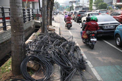 Pengendara melintas di dekat tumpukan kabel jaringan utilitas di kawasan Mampang, Jakarta Selatan, Senin (5/6/2023). Foto: Fitra Andrianto/kumparan