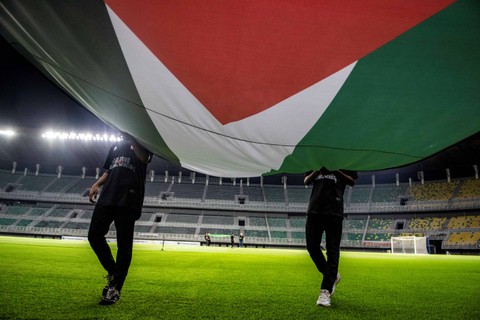 Petugas membawa bendera kebangsaan Palestina saat melakukan gladi resik dan latihan tim sepak bola Palestina jelang pertandingan sepak bola persahabatan (FIFA Matchday) antara Timnas Indonesia melawan tim sepak bola Palestina. Foto: Muhammad Adimaja/Antara Foto