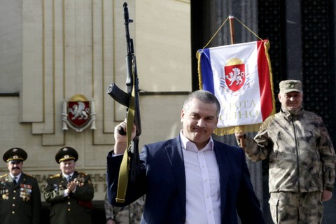 Penjabat pemimpin Krimea Sergei Aksyonov (Tengah) memegang model senapan otomatis AK-47 selama perayaan Hari Pembela Tanah Air di kota Simferopol Krimea pada 23 Februari 2015. Foto: MAX VETROV/AFP