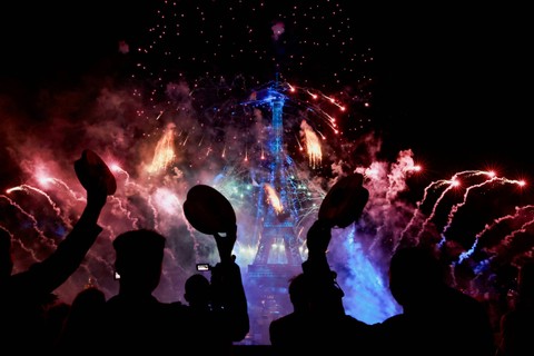 Orang-orang menyaksikan kembang api meledak di sekitar Menara Eiffel dalam perayaan untuk menandai Hari Bastille, di Paris, Prancis, Jumat (14/7/2023). Foto: Pascal Rossignol/REUTERS