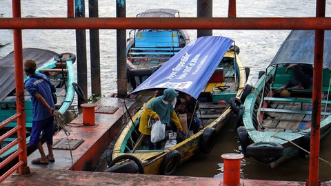Seorang warga yang menggunakan transportasi kapal getek di Pelabuhan 16 Ilir yang baru diresmikan, Minggu (16/7) Foto: ary priyanto/urban id