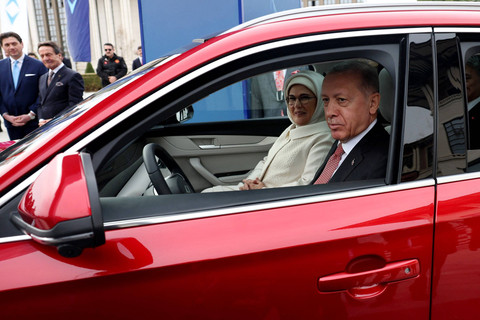 Presiden Turki Recep Tayyip Erdogan (kanan) dan istrinya Emine Erdogan duduk di Togg T10X, mobil listrik produksi dalam negeri pertama Turki di Kompleks Kepresidenan di Ankara, Turki, Senin (3/4/2023).  Foto: Adem ALTAN / AFP