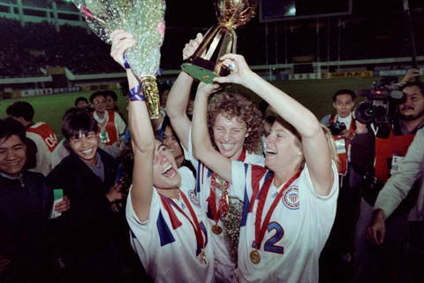 Pemain AS Michelle Akers-Stahl dan rekan setimnya Julie Foudy dan Carin Jennings merayakan kemenangan 2-1 mereka atas Norwegia pada pertandingan final turnamen sepak bola Piala Dunia Wanita pertama di Guangzhou pada 30 November 1991. Foto: Tommy Cheng/AFP 