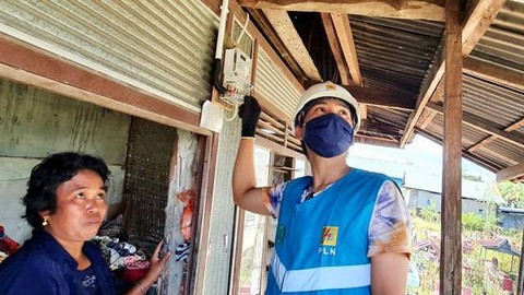 Petugas PLN menyambungkan listrik gratis untuk warga tak mampu.