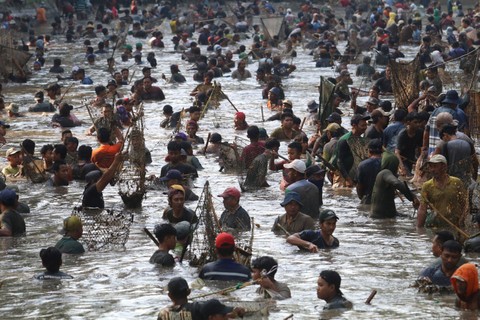 Sejumlah warga menangkap ikan saat tradisi Grobyak Ikan di Sumber Gundi, Desa Tanjung, Kediri, Jawa Timur, Minggu (30/7/2023). Foto: Prasetia Fauzani/Antara Foto